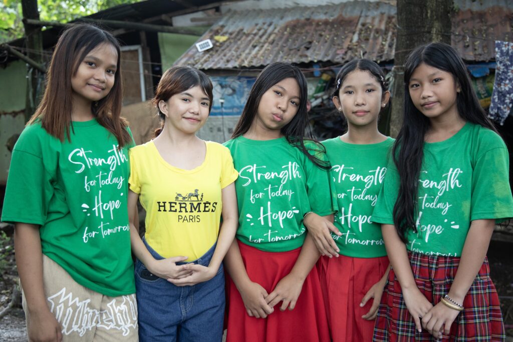 Five young girls in colorful shirts promote messages of strength and hope in a community setting.